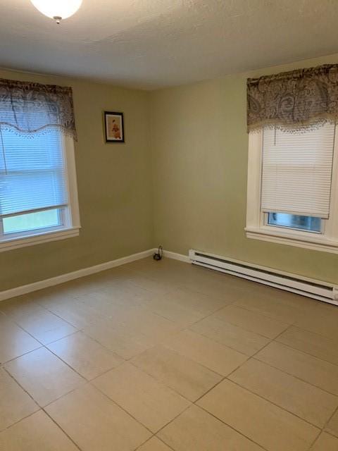 spare room featuring light tile patterned flooring and a baseboard radiator