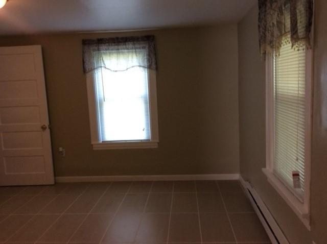 empty room featuring tile patterned flooring and baseboard heating