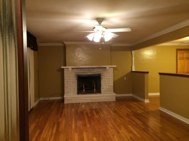 unfurnished living room featuring ornamental molding, a fireplace, hardwood / wood-style flooring, and ceiling fan