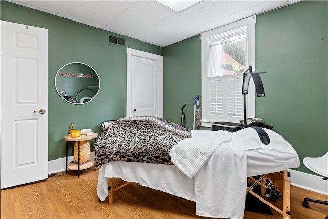 bedroom featuring light hardwood / wood-style floors and a paneled ceiling