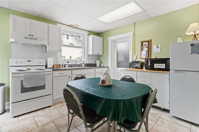 kitchen featuring light tile patterned floors, white cabinets, a paneled ceiling, and white appliances