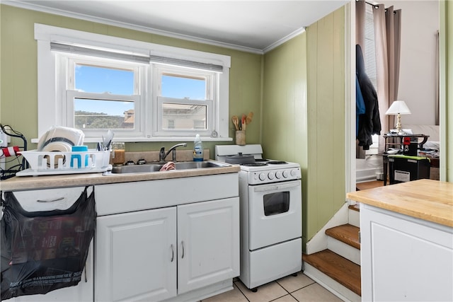 kitchen with white gas range oven, white cabinets, sink, light tile patterned floors, and ornamental molding