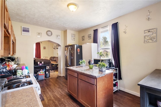 kitchen with dark hardwood / wood-style flooring, white stove, stainless steel refrigerator, and a textured ceiling