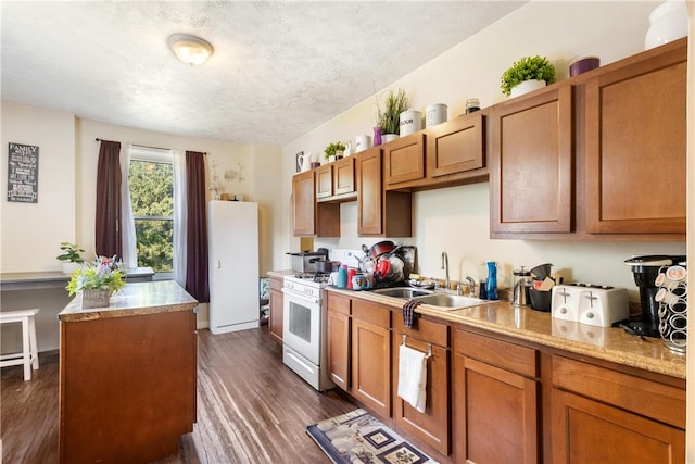 kitchen featuring sink, a textured ceiling, dark wood-type flooring, and white appliances