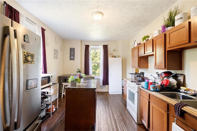 kitchen with appliances with stainless steel finishes, sink, dark hardwood / wood-style floors, a textured ceiling, and a center island