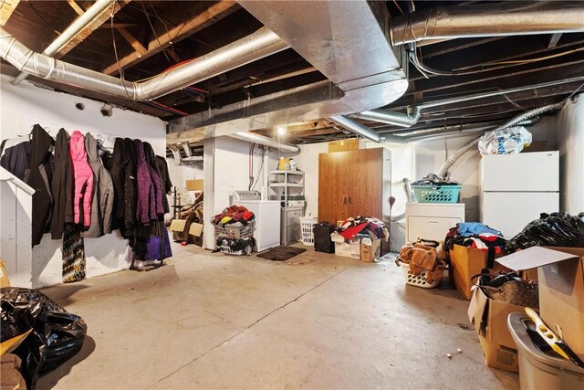 basement featuring white fridge and washing machine and clothes dryer