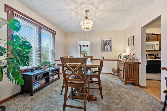 dining area with light colored carpet and a textured ceiling