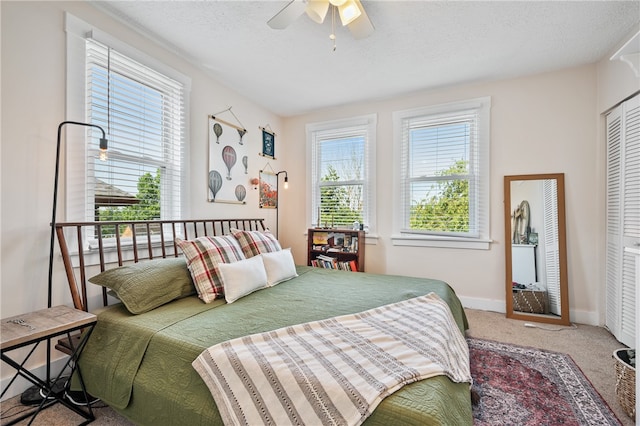 carpeted bedroom with ceiling fan, a closet, and a textured ceiling