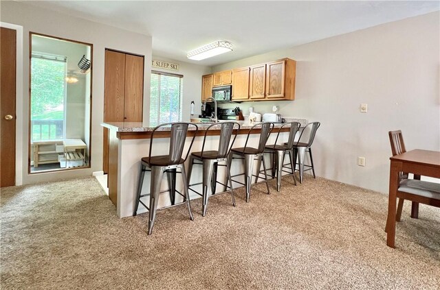 kitchen featuring sink, light colored carpet, a breakfast bar area, and kitchen peninsula