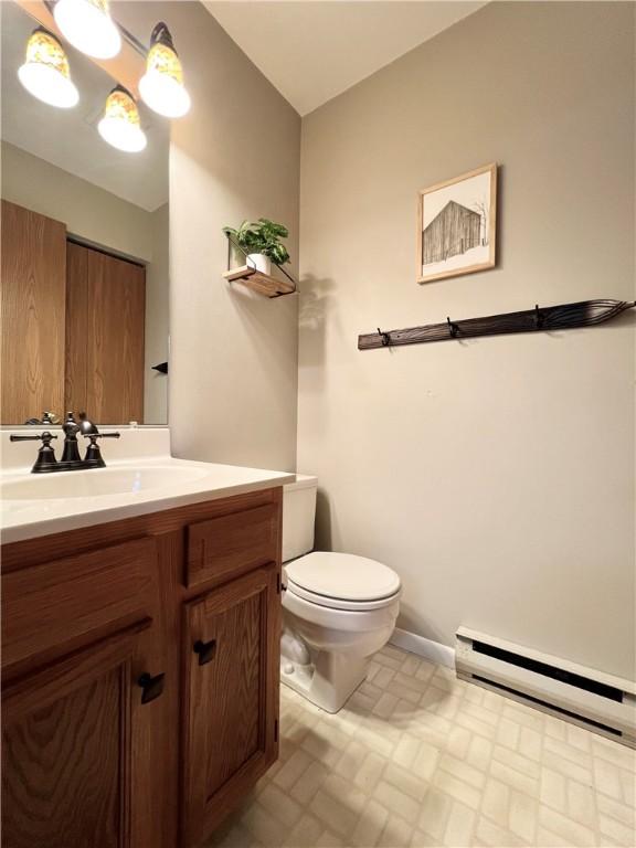 bathroom with vanity, a baseboard heating unit, toilet, and tile patterned floors