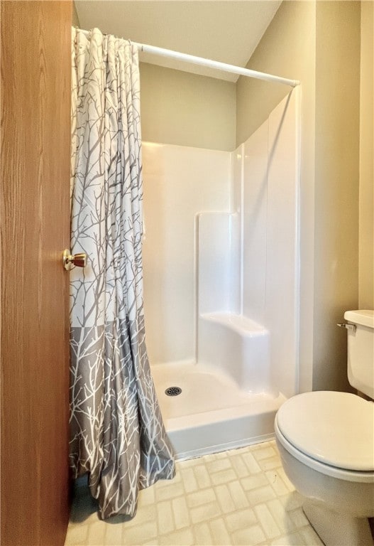 bathroom with curtained shower, tile patterned floors, and toilet