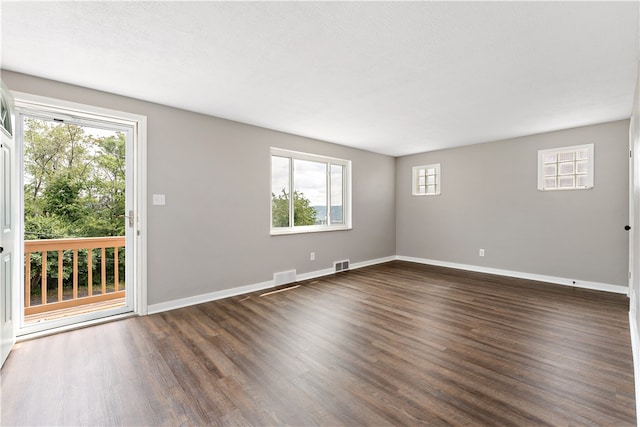 unfurnished room featuring dark wood-type flooring and a healthy amount of sunlight