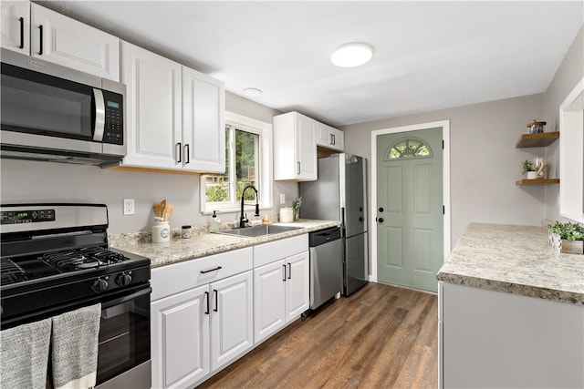 kitchen with dark hardwood / wood-style flooring, stainless steel appliances, white cabinetry, and sink