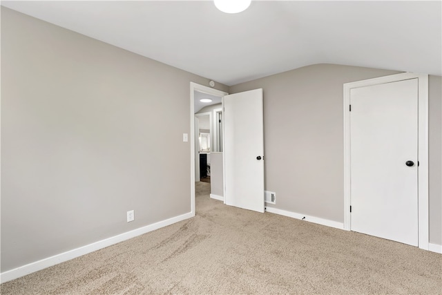 unfurnished bedroom with lofted ceiling and light carpet