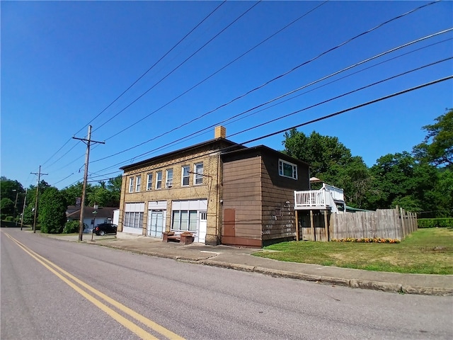 view of front facade featuring a garage, a deck, and a front lawn