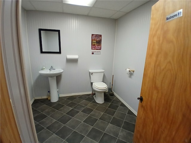 bathroom featuring tile patterned flooring, toilet, a drop ceiling, and sink