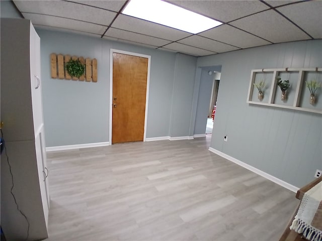 spare room featuring a paneled ceiling and light hardwood / wood-style floors