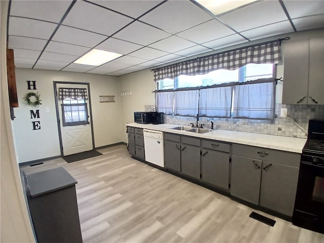 kitchen with black appliances, a paneled ceiling, light hardwood / wood-style floors, and sink