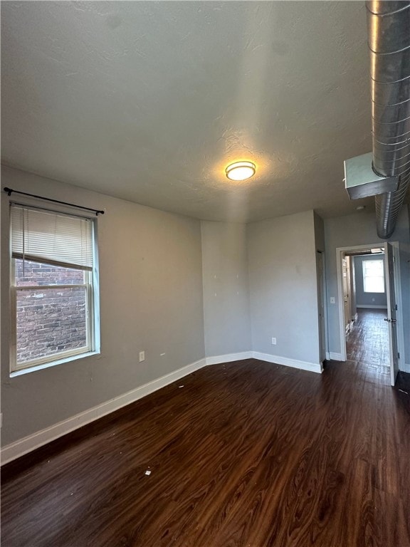 unfurnished room with a wood stove and dark wood-type flooring