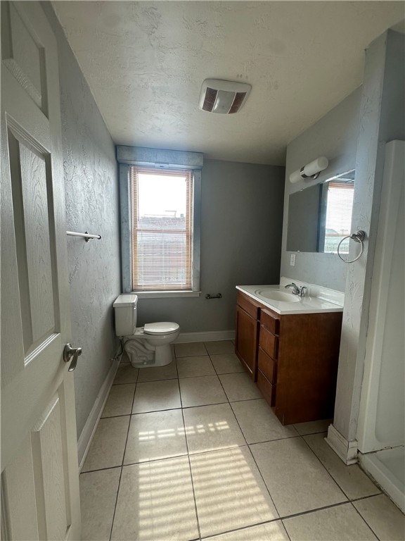 bathroom with a wealth of natural light, vanity, tile patterned floors, and toilet