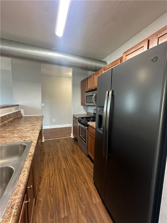 kitchen with stainless steel appliances, dark hardwood / wood-style flooring, and sink