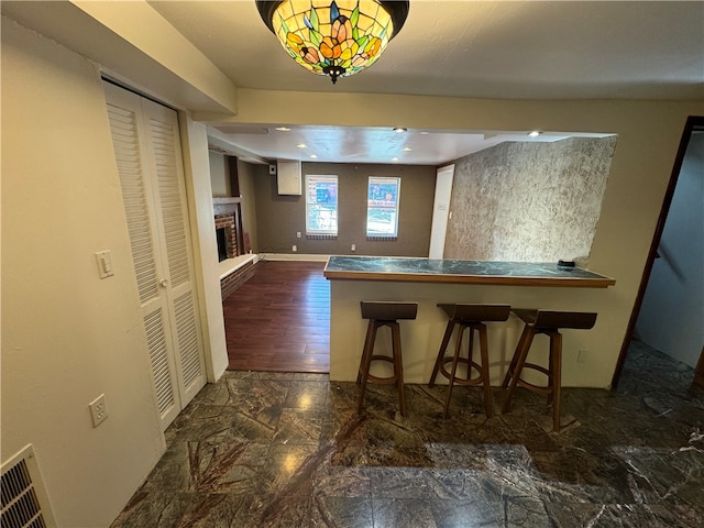 kitchen featuring a breakfast bar, dark hardwood / wood-style flooring, and a brick fireplace