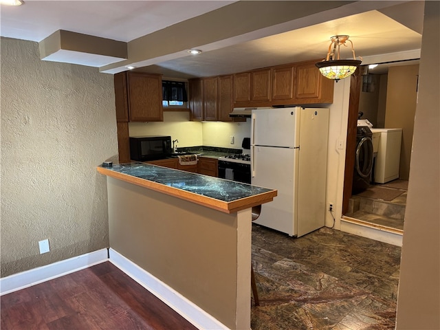 kitchen with washing machine and clothes dryer, dark hardwood / wood-style floors, kitchen peninsula, white appliances, and a kitchen bar