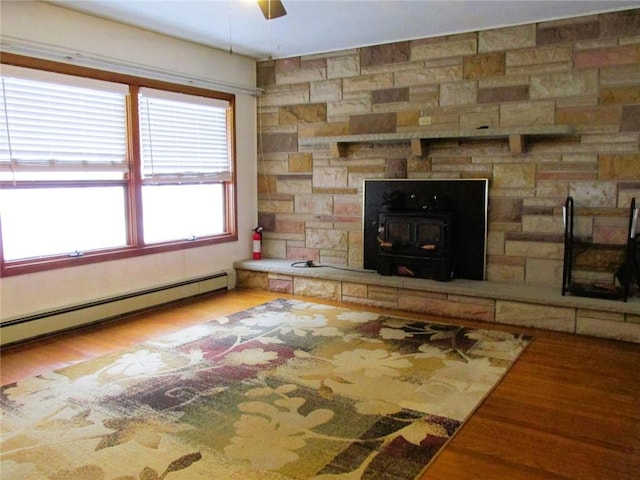 unfurnished living room with ceiling fan, hardwood / wood-style floors, and baseboard heating