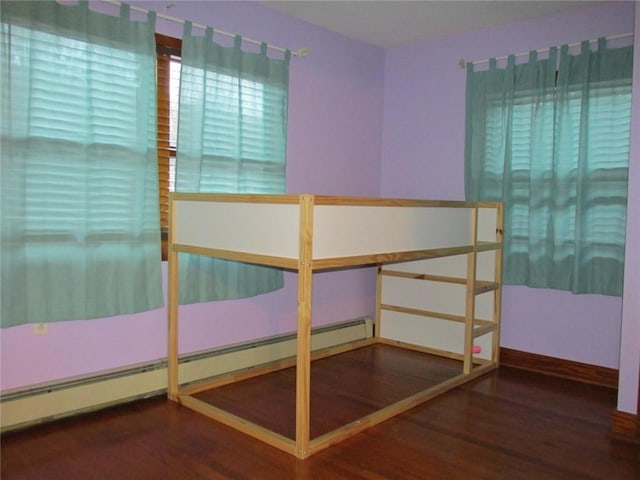 unfurnished bedroom with a baseboard radiator and wood-type flooring