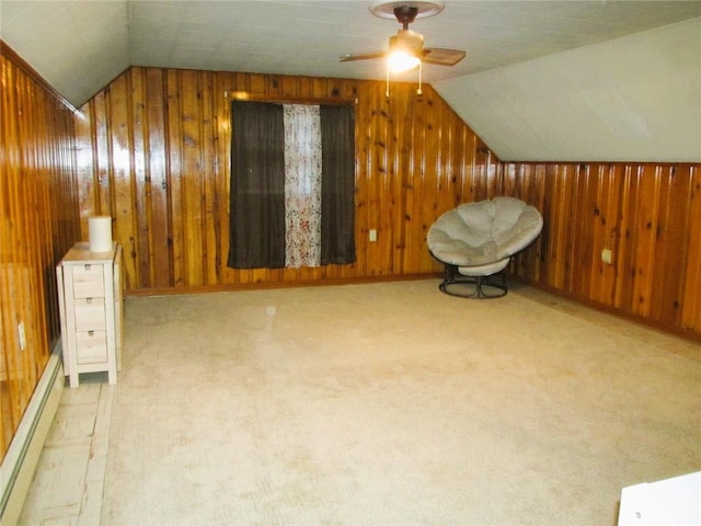 additional living space featuring baseboard heating, light colored carpet, lofted ceiling, and wood walls