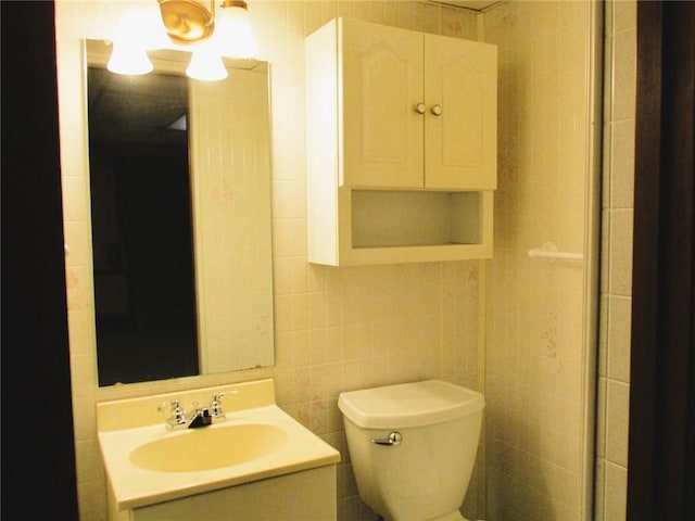 bathroom with vanity, toilet, and tile walls