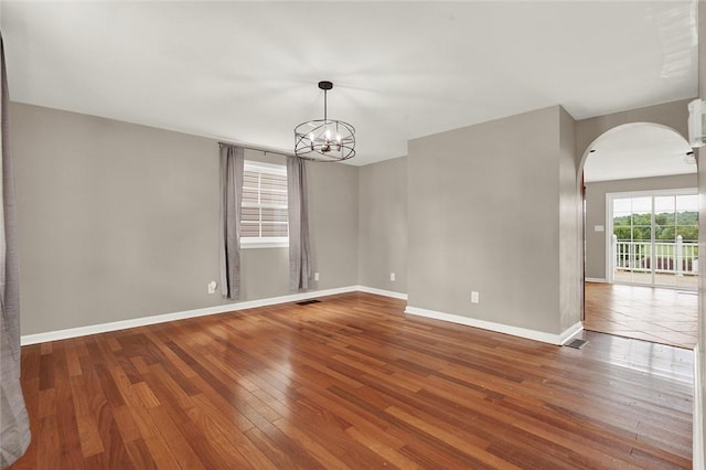 empty room with wood-type flooring and a chandelier