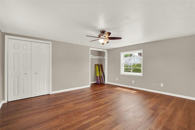 unfurnished bedroom with multiple closets, ceiling fan, and dark hardwood / wood-style flooring