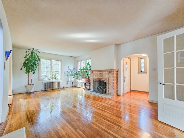 unfurnished living room featuring a fireplace, radiator heating unit, and light hardwood / wood-style floors