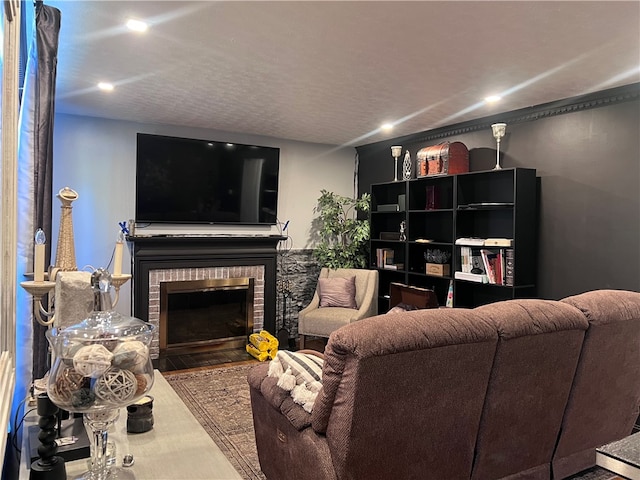 living room featuring a textured ceiling, wood-type flooring, and a brick fireplace