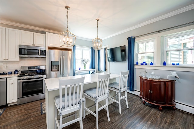 kitchen with appliances with stainless steel finishes, tasteful backsplash, white cabinets, decorative light fixtures, and a notable chandelier