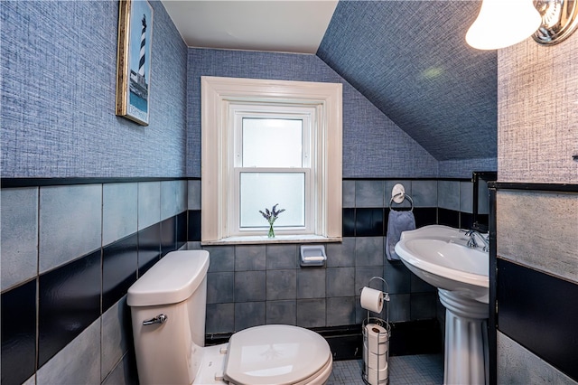 bathroom with tile patterned floors, tile walls, lofted ceiling, and toilet