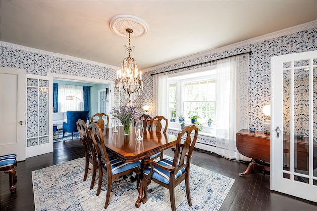 dining space with dark hardwood / wood-style floors, ornamental molding, and an inviting chandelier