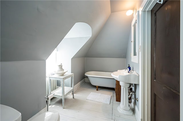 bathroom featuring a bathing tub, lofted ceiling, and hardwood / wood-style floors