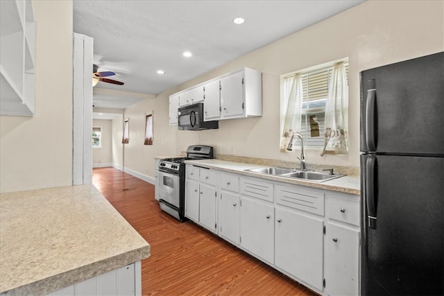 kitchen featuring white cabinets, black appliances, light wood-type flooring, and sink