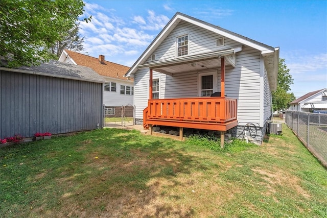 rear view of property featuring a lawn, cooling unit, and a deck