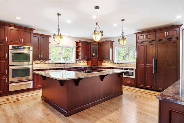 kitchen featuring a kitchen island, light stone counters, stainless steel double oven, and a breakfast bar