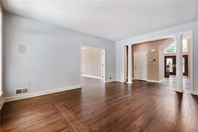 unfurnished room featuring ornate columns and dark wood-type flooring