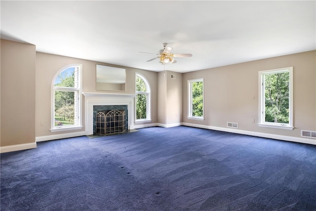 unfurnished living room with dark carpet, plenty of natural light, and ceiling fan