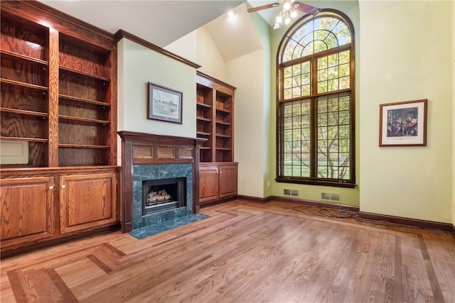 unfurnished living room featuring ceiling fan, light hardwood / wood-style flooring, vaulted ceiling, and a high end fireplace