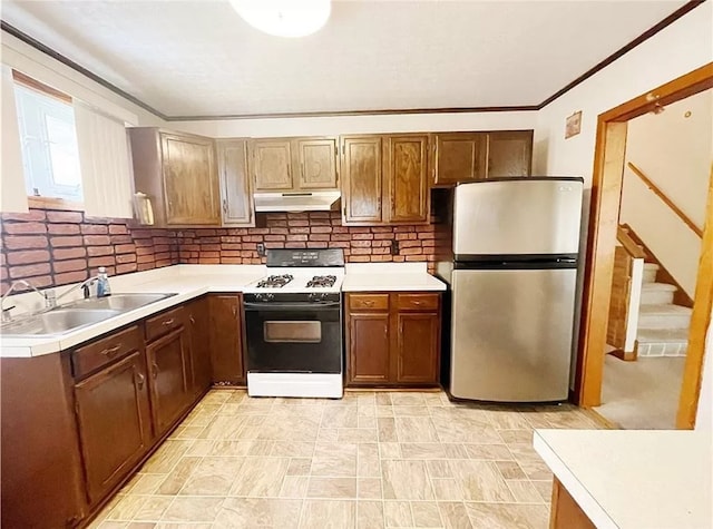 kitchen featuring sink, stainless steel refrigerator, white gas range oven, and tasteful backsplash