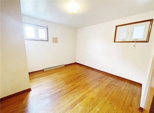 unfurnished room featuring a baseboard heating unit and light wood-type flooring