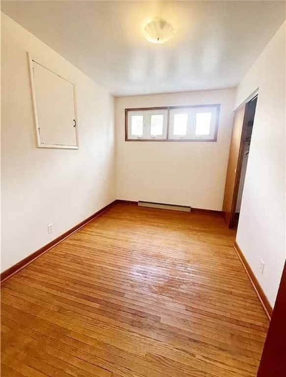 spare room with a baseboard radiator and light hardwood / wood-style flooring