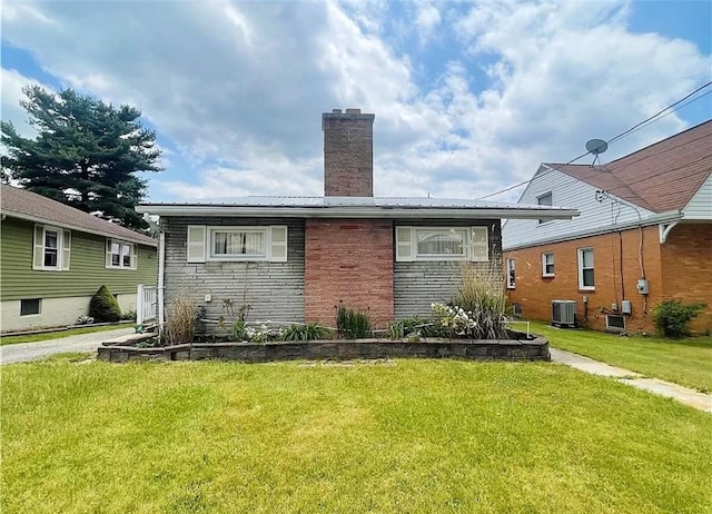 rear view of house featuring central AC unit and a yard