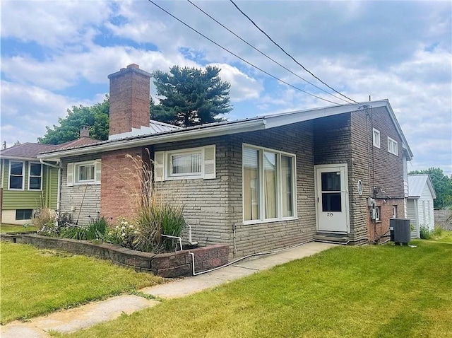 rear view of house featuring central AC and a yard